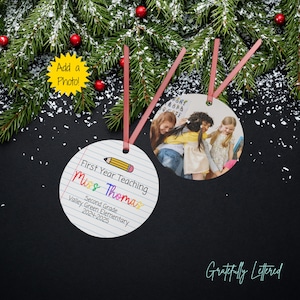 May include: Two round ornaments with red ribbon hangers. One ornament features a lined paper design with a pencil graphic and text reading First Year Teaching, Miss Thomas, Second Grade, Valley Green Elementary, 2024-2025. The other displays a photo.
