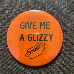May include: Orange round button with the text "GIVE ME A GLIZZY" in black text. A black outline of a hot dog is below the text.