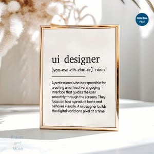 May include: A rectangular gold-toned frame containing a white print with black text that defines the term ui designer. The text includes the phonetic pronunciation, the noun classification, and a descriptive paragraph about the profession.