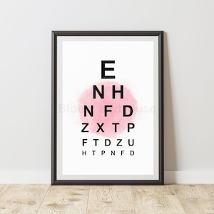Può includere: Stampa incorniciata di un grafico oculistico con lettere nere su sfondo bianco. Le lettere sono disposte in ordine decrescente di dimensione, con un lavaggio ad acquerello rosa dietro il centro del grafico. La cornice è nera.