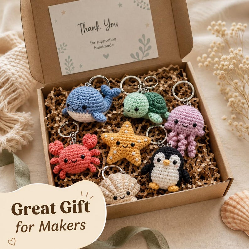 May include: A cardboard gift box containing six crocheted keychains shaped like a blue whale, green turtle, pink jellyfish, red crab, yellow starfish, beige seashell, and a black and white penguin. A card inside reads Thank You for supporting handmade.