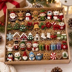 May include: A collection of small, crocheted Christmas ornaments arranged in a cardboard box. The set includes figures of Santa, reindeer, snowmen, gingerbread people, elves, penguins, polar bears, nutcrackers, angels, and various holiday icons like trees, wreaths, bells, gifts, and cocoa mugs.