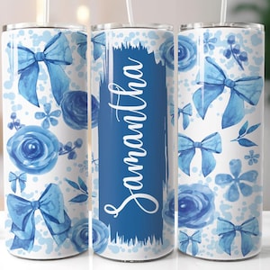 May include: Three stainless steel tumblers with a white background and blue watercolor designs. The designs include flowers, bows, and the name "Samantha".