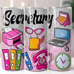 Può includere: Un bicchiere di glitter argentato con un design rosa e nero che presenta la parola "Segretaria" e vari articoli da ufficio, tra cui una stampante, un telefono, un calendario, un laptop e un orologio.
