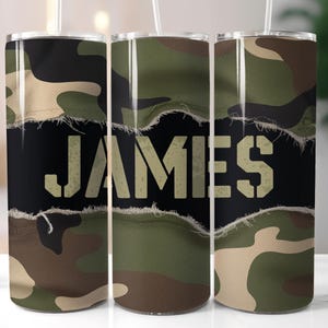 Pode incluir: Três copos de aço inoxidável com um padrão de camuflagem e o nome "JAMES" impresso em branco sobre um fundo preto.