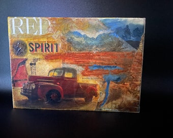 May include: A collage artwork featuring a red vintage pickup truck, a mountain range, and the words "RED SPIRIT" in bold, red letters. The artwork has a rustic, vintage feel and is likely inspired by the American West.