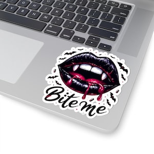 May include: A sticker depicting black lips with fangs and dripping red blood. The words "Bite Me" are written in a stylized font below the lips. Small bat silhouettes surround the lips.