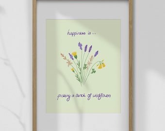 May include: A framed print with a light green background and a bouquet of wildflowers. The text reads "happiness is... picking a bunch of wildflowers" in purple script. The frame is made of wood.