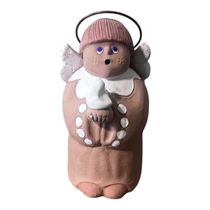 May include: A ceramic angel figurine with a halo, wings, and a surprised expression. The angel wears a pink hat, blue eyes, and a white collar. The body is a light brown color with white accents.