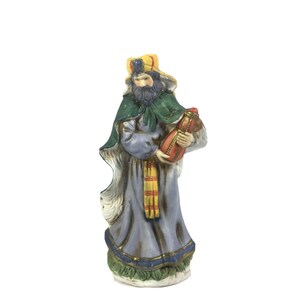 Puede incluir: Figura de cerámica de un rey mago, parte de un belén. La figura viste una túnica azul, capa verde y tocado amarillo. Sostiene un recipiente rojo y dorado. La base está decorada con detalles verdes y azules. La figura mide aproximadamente 13 cm de altura.