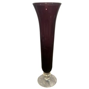 May include: A tall, elegant vase with a flared top and a slender body. The vase is a deep purple color, with a gradient that darkens towards the base. It has a clear, circular base and is likely made of glass.