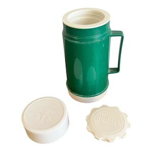 May include: A green Thermos brand insulated food jar with a white lid and a white lid with the Thermos logo.