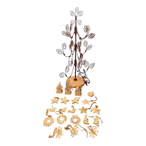 Puede incluir: Un soporte de adornos de árbol de Navidad de alambre rústico con una base de madera. El soporte está decorado con 20 adornos de madera, incluyendo pájaros, estrellas, coronas y copos de nieve.