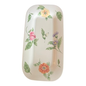 Könnte beinhalten: Weiße rechteckige Servierplatte mit floralem Design. Die Platte zeigt rosa Rosen, gelbe und orangefarbene Blumen, grüne Blätter und einen weißen Schmetterling.