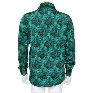 May include: A long-sleeved shirt with a striking green pattern. The design showcases a repeating motif of layered, textured shapes in shades of teal and dark green. The shirt has a classic collar and buttoned cuffs.