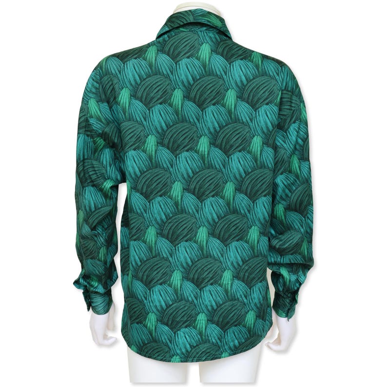 May include: A long-sleeved shirt with a striking green pattern. The design showcases a repeating motif of layered, textured shapes in shades of teal and dark green. The shirt has a classic collar and buttoned cuffs.