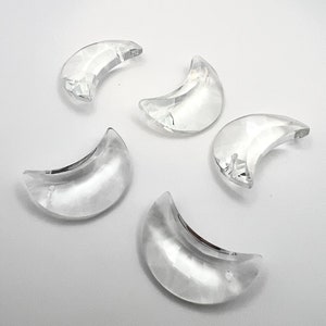 May include: Five clear crystal crescent moon shaped charms. The charms are approximately 1 inch in length.