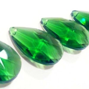 Puede incluir: Cinco prismas de cristal en forma de lágrima de color verde vibrante. Los prismas son facetados y reflejan la luz.