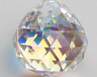 May include: A clear crystal ball with a faceted design. The ball is iridescent and reflects light in a rainbow of colors.