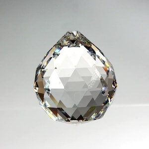 May include: A clear crystal ball with a faceted design. The ball is round and has a smooth surface. It is a decorative object that can be used to reflect light.