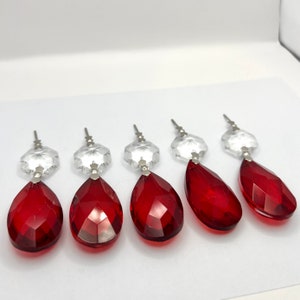 Puede incluir: Cinco prismas de araña de cristal rojo en forma de lágrima con tapas de cristal transparente.
