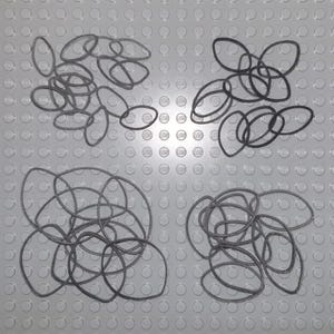 May include: Four piles of black rubber bands on a gray surface with a repeating pattern of small circles.