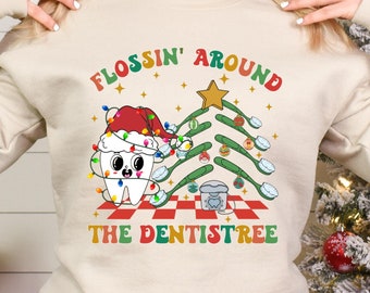 May include: A white sweatshirt with a Christmas-themed design featuring a tooth with a Santa hat and a toothbrush tree. The text reads "Flossin' Around The Dentistree".