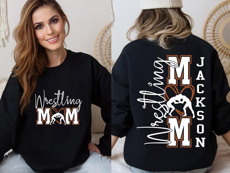 以下が含まれることがあります： 黒色のスウェットシャツ。白の筆記体とブロック体で「Wrestling Mom」の文字とレスリングのグラフィックがプリントされています。スウェットシャツの背面には「Wrestling Mom」の文字と「Jackson」の名前がプリントされています。
