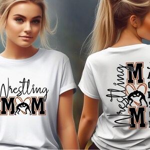 以下が含まれることがあります： 黒いスクリプトとブロック文字で「Wrestling MOM」とレスリングのグラフィックが描かれた白いTシャツ。シャツの背面には、同様のデザインで「Wrestling MOM Jackson」と表示されています。