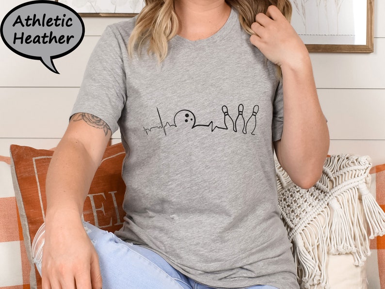 Puede incluir: Una camiseta gris jaspeada con un gr&aacute;fico negro de una bola de bolos y bolos con una l&iacute;nea de latido del coraz&oacute;n. El gr&aacute;fico dice "Bowling is my therapy".