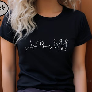 Puede incluir: Camiseta negra con un gr&aacute;fico blanco de una bola de bolos y bolos con una l&iacute;nea de latido del coraz&oacute;n.