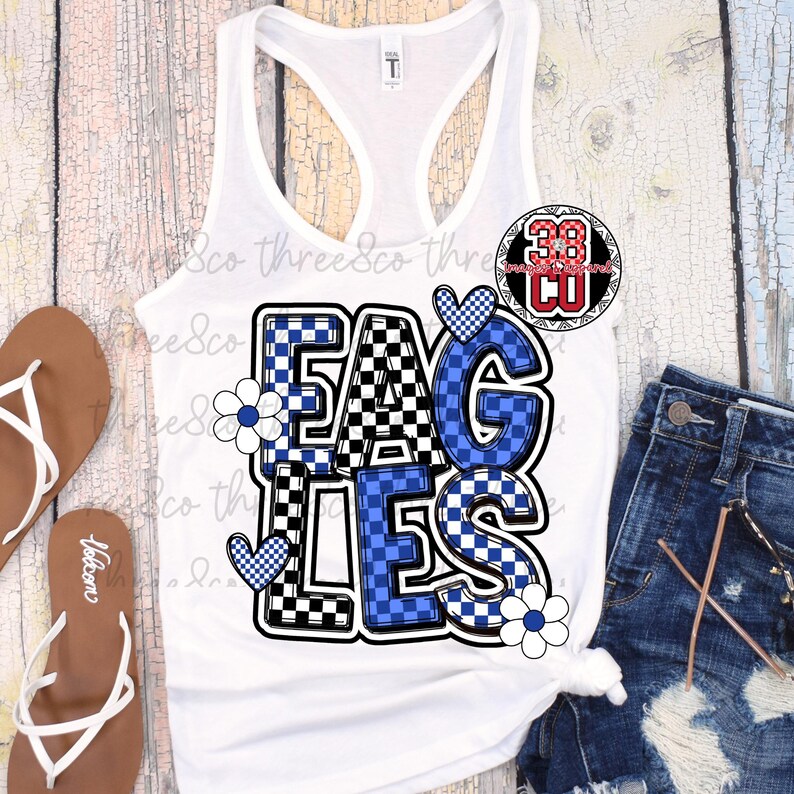 Puede incluir: Camiseta sin mangas blanca con la palabra "EAGLES" en un dise&ntilde;o a cuadros azul y negro. Las letras est&aacute;n delineadas en negro y decoradas con corazones azules y flores blancas. La camiseta sin mangas se combina con pantalones cortos de mezclilla y sandalias.