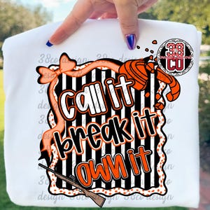 May include: White sweatshirt with a graphic design featuring the words "Call it, Break it, Own it" in a bold, orange and black design. The design includes a shotgun, clay target, and decorative elements.