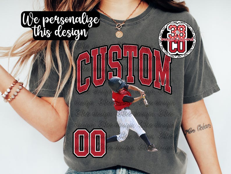 May include: Gray t-shirt with a baseball design. The word "CUSTOM" is in large red letters, with a baseball player graphic. The number "00" is at the bottom, and the text "We personalize this design" is at the top.