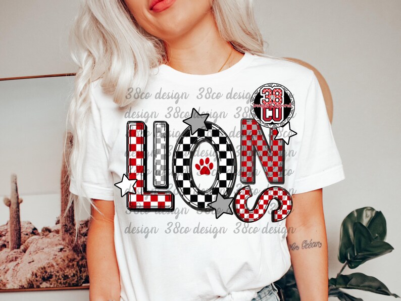 以下が含まれることがあります： 赤、黒、グレーのチェック柄で「LIONS」の文字がプリントされた白いTシャツ。「O」の文字には足跡が描かれています。数字の「38」が文字の上に円で囲まれています。グレーの星が文字の周りにあります。