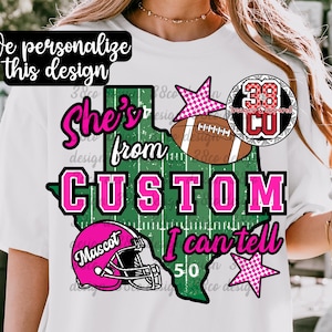 May include: A white t-shirt featuring a graphic of the state of Texas in green with white yard lines. The text reads "She's from CUSTOM I can tell" in pink and black. Includes a brown football, a pink football helmet, and two pink stars.