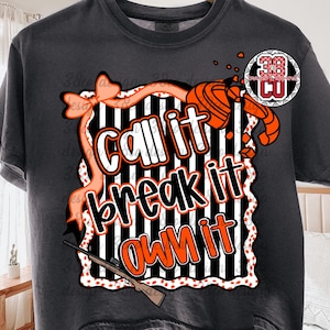 May include: Dark gray t-shirt with a graphic design that says "Call it, break it, own it." The design includes a bow, a shotgun, and a clay target. The text is in white and orange.