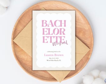 May include: A bachelorette weekend invitation card with pink text on a white background, scalloped edges, and a kraft paper envelope, resting on a wooden plate. The invitation reads "BACHELORETTE Weekend".