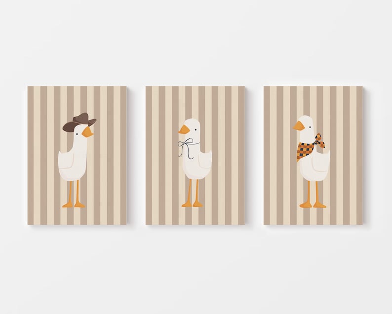 May include: Three printable wall art prints featuring a white goose with different accessories. The first goose is wearing a brown cowboy hat, the second goose is wearing a black and orange bow, and the third goose is wearing a red and black checkered scarf. The background of each print is a light brown with vertical stripes.