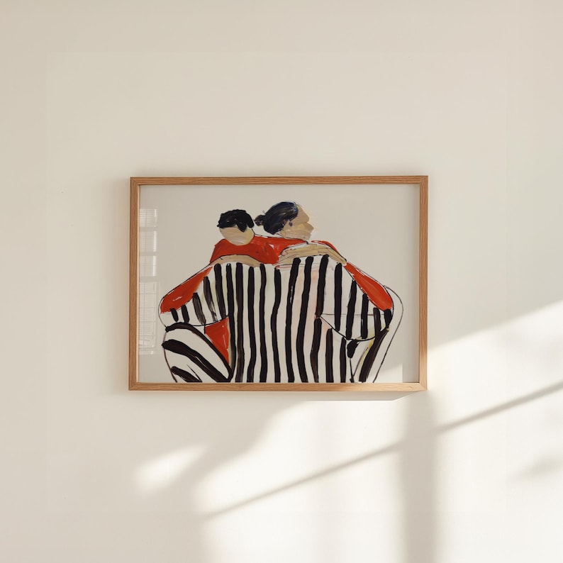 K&ouml;nnte beinhalten: Ein gerahmter Kunstdruck mit einer abstrakten Illustration von zwei sich umarmenden Figuren. Die Figuren tragen rote Oberteile und schwarz-wei&szlig; gestreifte Unterteile. Das Kunstwerk ist vor einem neutralen Hintergrund platziert.