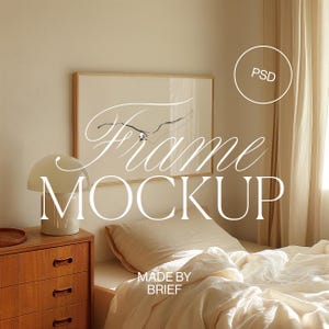 Op de afbeelding: Een witte frame mockup met een eenvoudig zwart-wit abstract ontwerp erin. De frame is op een witte muur boven een bed met witte lakens en een houten nachtkastje.