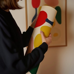 Puede incluir: Un p&oacute;ster enrollado con un dise&ntilde;o abstracto colorido con formas rojas, amarillas, azules y rosas sobre un fondo crema.