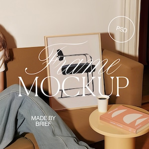 May include: A framed print of a black and white abstract drawing of a chair. The frame is made of wood and has a light brown finish. The print is sitting on a brown sofa with a white coffee table in front of it. The coffee table has a book and a white coffee cup on it. The text "Frame Mockup" is written in white letters on the image. The text "Made by Brief" is written in white letters on the image.