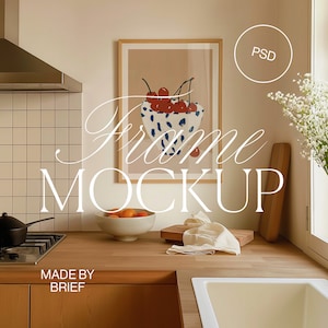 Puede incluir: Una impresión enmarcada de un cuenco de cerezas rojas con un patrón blanco y azul sobre una encimera de cocina marrón claro. La impresión está en un marco de madera. El texto "Frame Mockup" está escrito en blanco sobre la encimera. El texto "Made by Brief" está escrito en blanco en una puerta de armario.
