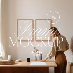 Può includere: Due cornici in legno con passepartout bianchi su una parete bianca. Una donna è in piedi davanti alle cornici, mentre posiziona un foglio di carta su un tavolo di legno. Il tavolo ha un vaso di ceramica bianca con fiori secchi, una bottiglia di ceramica bianca e una tazza di ceramica marrone. Il testo "Frame Mockup" è scritto in bianco sul muro. Il testo "Made by Brief" è scritto in bianco sotto le cornici.