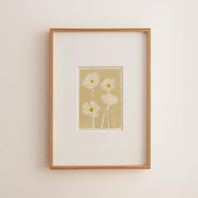 May include: A framed art print featuring four white flowers with yellow centers against a light yellow background. The artwork is encased in a white mat and a natural wood frame, creating a minimalist aesthetic.