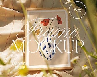 May include: A wooden frame with a light brown mat and a white background. The frame contains a painting of a blue and white ceramic vase with red and yellow flowers. The text "Frame Mockup" is written in white on the image. The text "Made by Brief" is written in black at the bottom of the image.