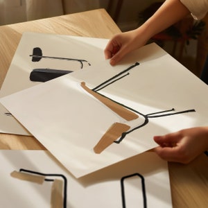 May include: Three white sheets of paper with black and brown abstract line drawings. The drawings are of chairs or other furniture.