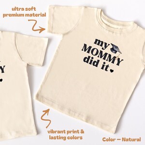 May include: A natural colored t-shirt with the text "my MOMMY did it." in black with a graduation cap graphic. The text "ultra soft premium material" is in the top left corner and "vibrant print & lasting colors" is in the bottom left corner. The text "Color - Natural" is in the bottom right corner.