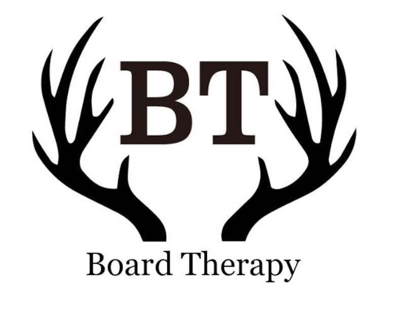 Puede incluir: Silueta negra de una cornamenta de ciervo con las letras "BT" en el centro y el texto "Board Therapy" debajo.